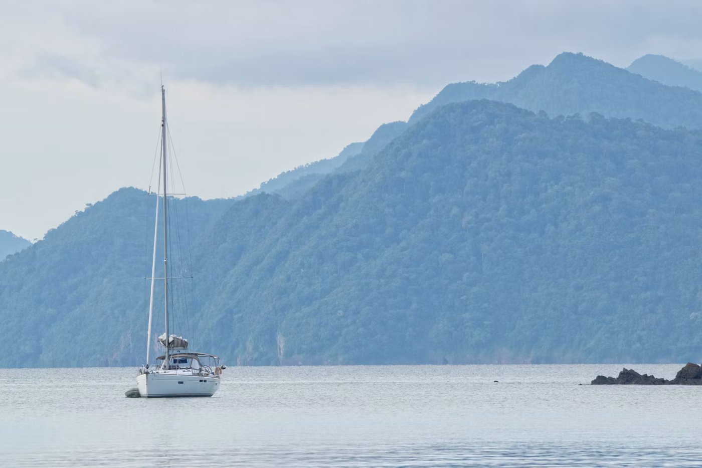 A sailing yacht against the forested hills of Langkawi
